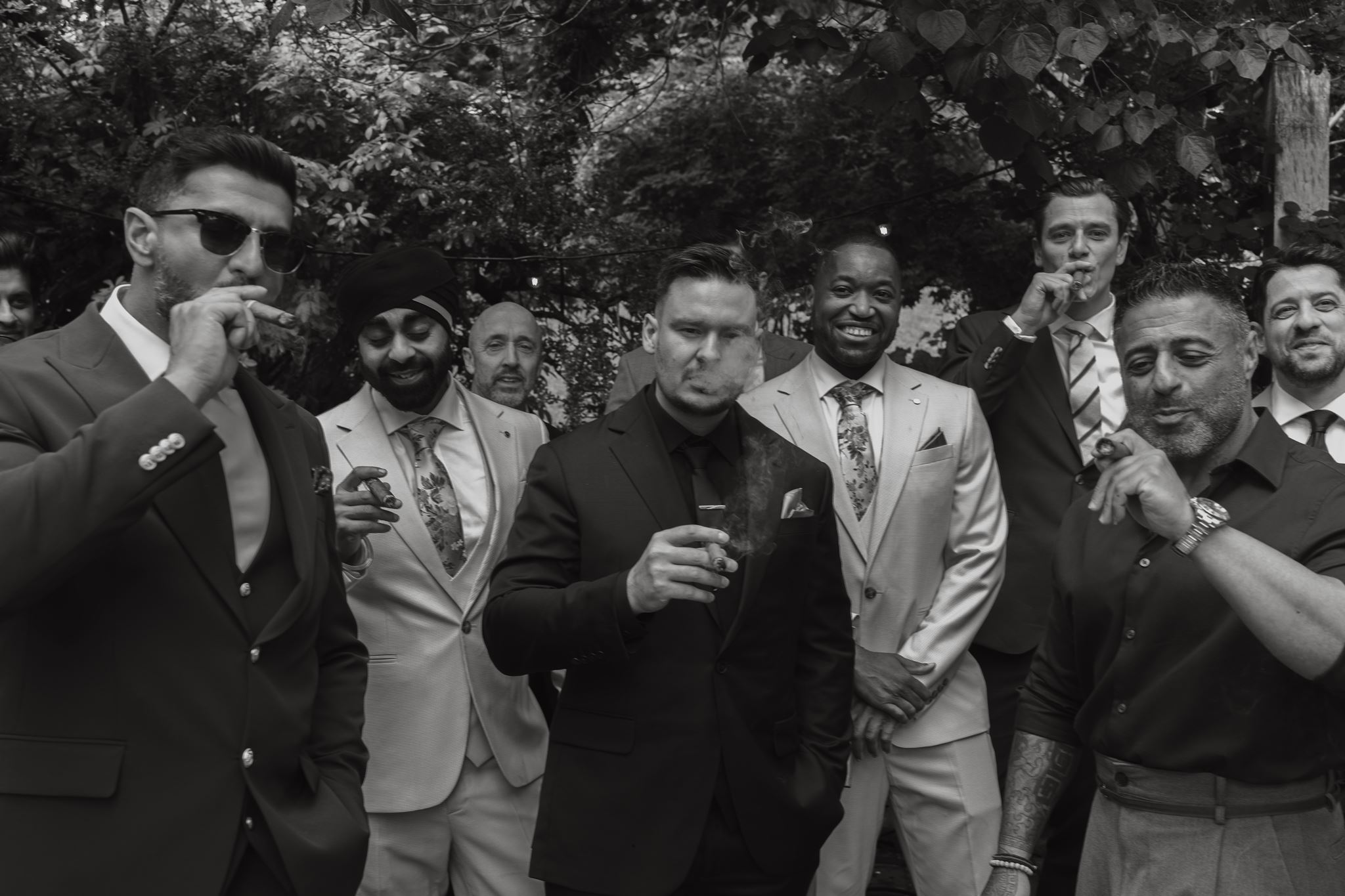 Groomsmen sharing cigars in the garden