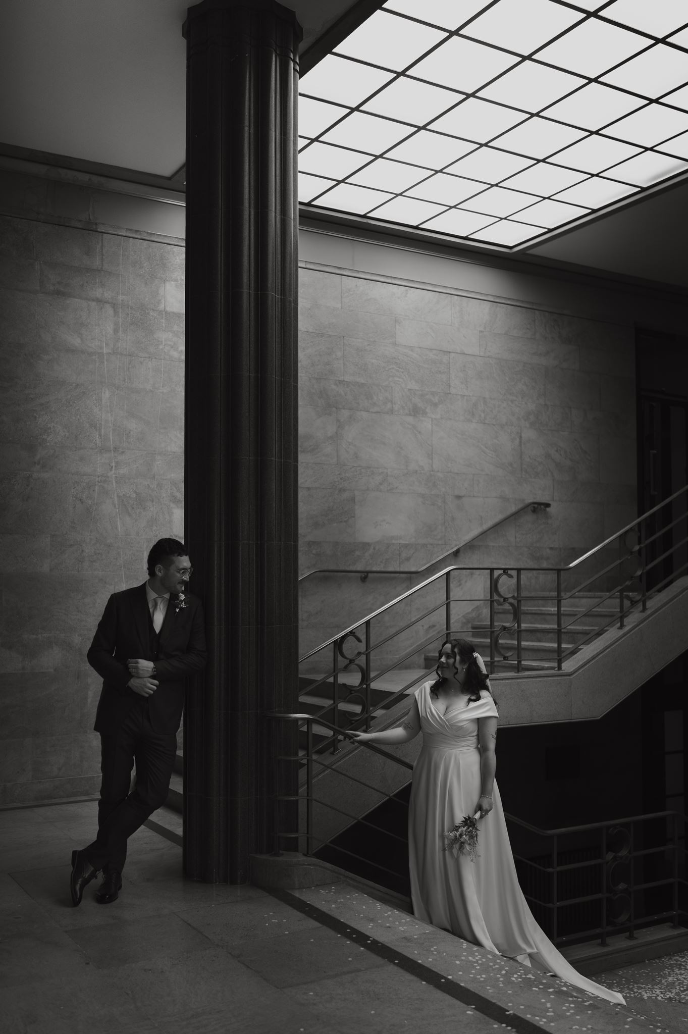 Bride and groom either side of a column in a marble stairwell