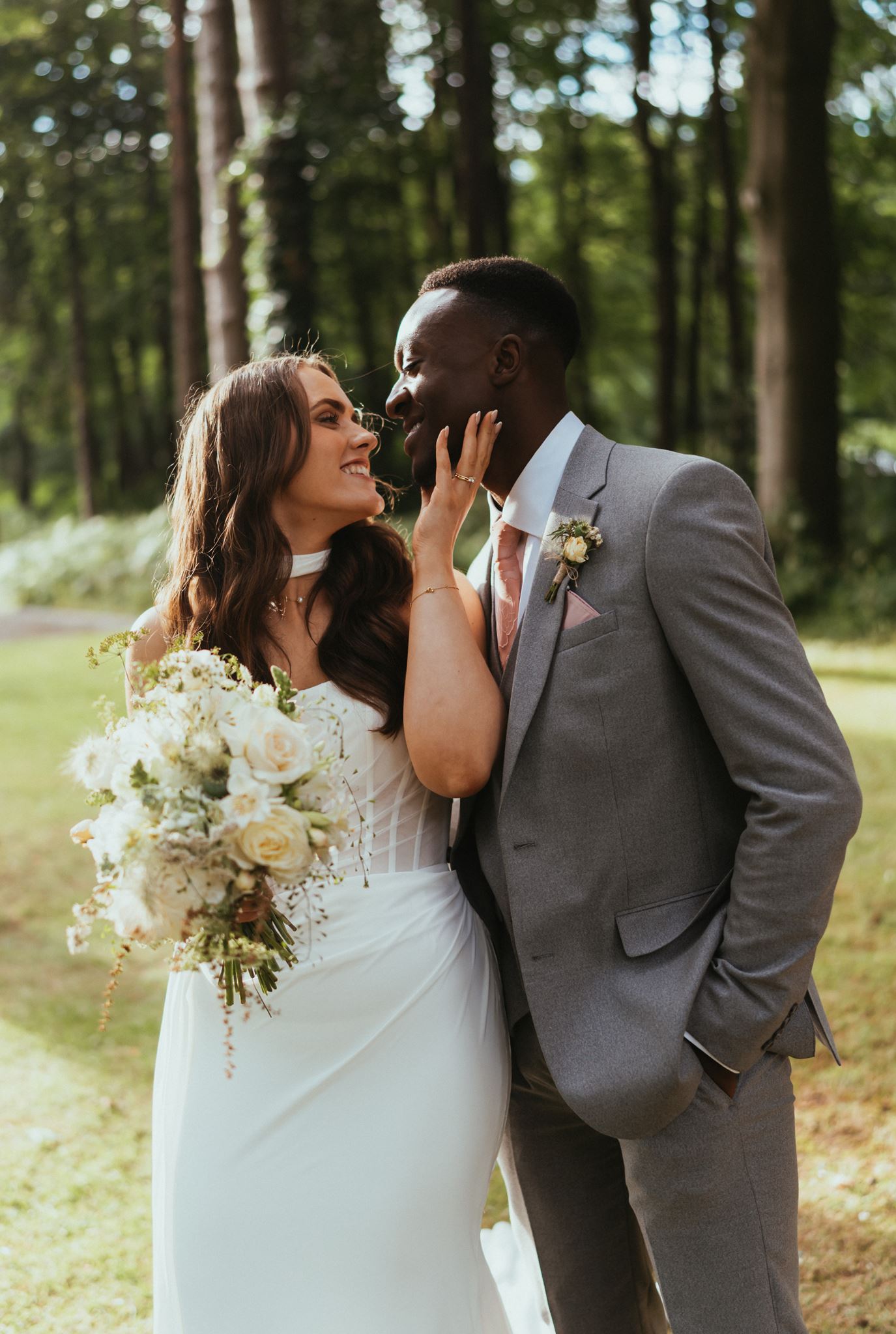 Bride touching her groom's face in woodland